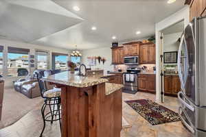 Kitchen with stainless steel appliances, an island with sink, a chandelier, a kitchen breakfast bar, and open floor plan