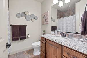 Bathroom featuring a shower with shower curtain, vanity, and stone tile floors