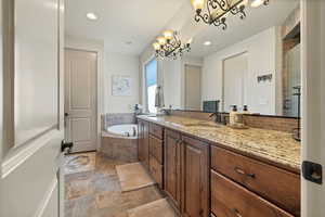 Bathroom featuring vanity, a garden tub, stone tile flooring, recessed lighting, and tasteful backsplash