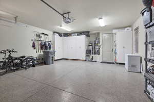 Garage with white refrigerator, secured water heater, and a garage door opener