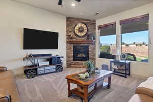 Carpeted living area with a stone fireplace, a ceiling fan, and recessed lighting