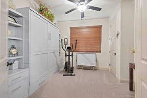 Workout area featuring light colored carpet and ceiling fan