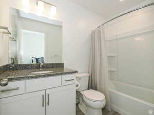 Full bath featuring shower / bathtub combination with curtain, vanity, and dark wood-type flooring
