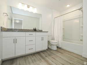 Full bath with double vanity, shower / bathtub combination with curtain, and light wood-style floors
