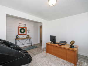 Home office featuring light wood-style floors, a textured ceiling, and wood walls