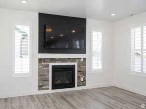 Detailed view of a glass covered fireplace, wood finished floors, and recessed lighting