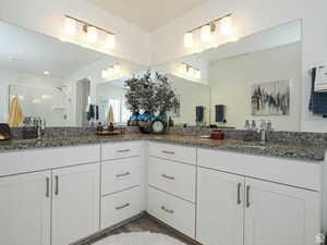 Full bath featuring a stall shower, double vanity, and light wood-type flooring