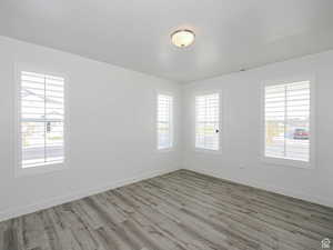 Unfurnished room with wood finished floors, plenty of natural light, and a textured ceiling
