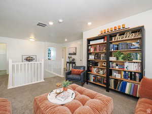 Sitting room with a textured ceiling, carpet, and an upstairs landing