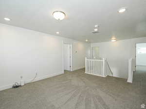 Carpeted empty room with a textured ceiling and recessed lighting
