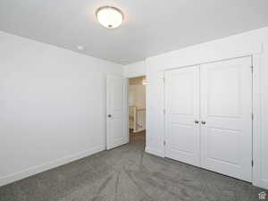 Unfurnished bedroom with carpet flooring, a closet, and a textured ceiling
