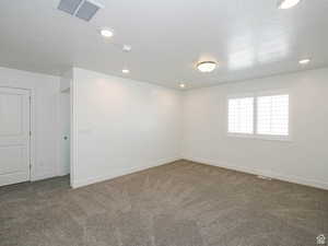 Carpeted spare room with a textured ceiling and recessed lighting