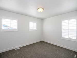 Unfurnished room featuring baseboards and dark colored carpet
