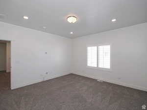 Empty room with dark colored carpet and recessed lighting