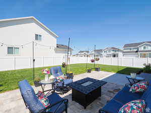 Fenced backyard with an outdoor fire pit, a patio area, and a residential view