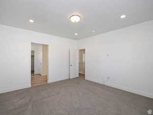 Unfurnished bedroom with carpet, a spacious closet, recessed lighting, and a textured ceiling