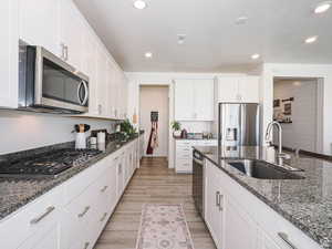 Kitchen with white cabinetry, dark stone counters, stainless steel appliances, recessed lighting, and a textured ceiling