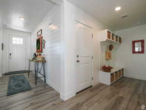 Entryway featuring wood finished floors, a textured ceiling, recessed lighting, and wood walls