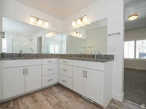Full bath with a shower stall, double vanity, and light wood finished floors