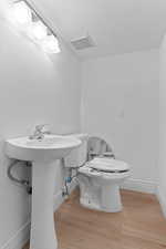 Half bathroom featuring light wood-style floors and a textured ceiling