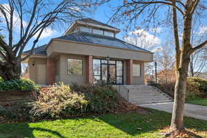 View of front of house featuring stairs, brick siding, a shingled roof, a front lawn, and stucco siding