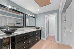 Bathroom with double vanity, light wood finished floors, and recessed lighting