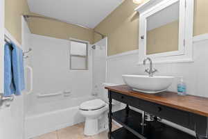 Bathroom featuring tub / shower combination, a wainscoted wall, light tile patterned floors, and vanity