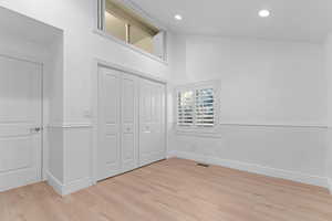 Unfurnished bedroom with light wood-type flooring, a closet, high vaulted ceiling, and recessed lighting