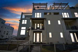Back of property with stucco siding, a balcony, and stairway