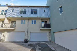 Rear view of property with a balcony, stucco siding, and a garage