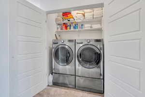 Laundry room with washing machine and clothes dryer and light colored carpet