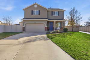 Traditional-style house featuring driveway, brick siding, covered porch, stucco siding, and an attached garage