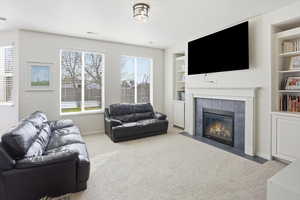 Carpeted living area featuring built in features and a tiled fireplace
