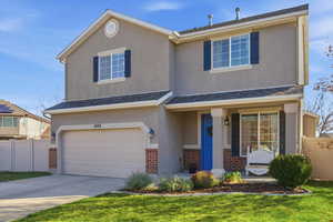 Traditional-style house with brick siding, an attached garage, a porch, stucco siding, and driveway