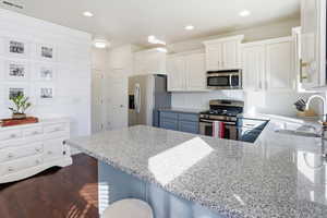Kitchen featuring white cabinetry, appliances with stainless steel finishes, light stone countertops, recessed lighting, and a peninsula