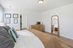 Bedroom featuring connected bathroom, arched walkways, and wood finished floors