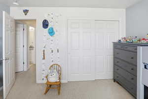 Bedroom featuring light carpet and a closet
