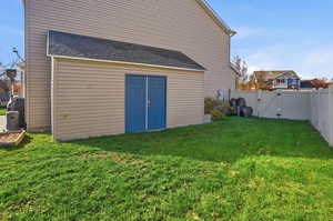 Rear view of property featuring a gate, a fenced backyard, and roof with shingles