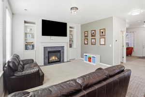 Carpeted living room with built in features and a tiled fireplace