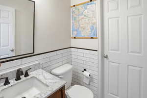 Half bath featuring vanity and tile walls