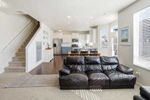 Living area featuring stairs, recessed lighting, and dark wood-style floors