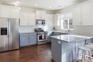 Kitchen with stainless steel appliances, a breakfast bar area, white cabinets, a peninsula, and recessed lighting