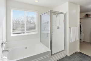 Full bathroom with a garden tub, dark tile patterned floors, a stall shower, and a walk in closet