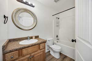 Full bathroom with vanity, shower / tub combination, and dark wood-style floors