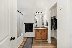 Bathroom with vanity, shower / tub combo with curtain, a spacious closet, and dark wood-type flooring