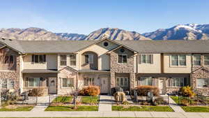 View of front of home featuring stone siding, a fenced front yard, a mountain view, stucco siding, and a residential view