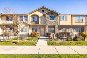 View of front of property featuring stucco siding, a fenced front yard, and stone siding