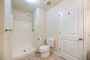 Bathroom featuring a shower stall, light tile patterned floors, and a textured ceiling