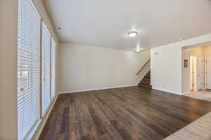 Unfurnished living room with wood finished floors and stairway