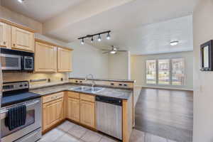 Kitchen with appliances with stainless steel finishes, light brown cabinets, decorative backsplash, and track lighting